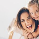 Single parent dating symbolized by mother carrying her child on her back and laughing into camera
