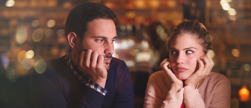 A couple in a cafe looking seriously at each other