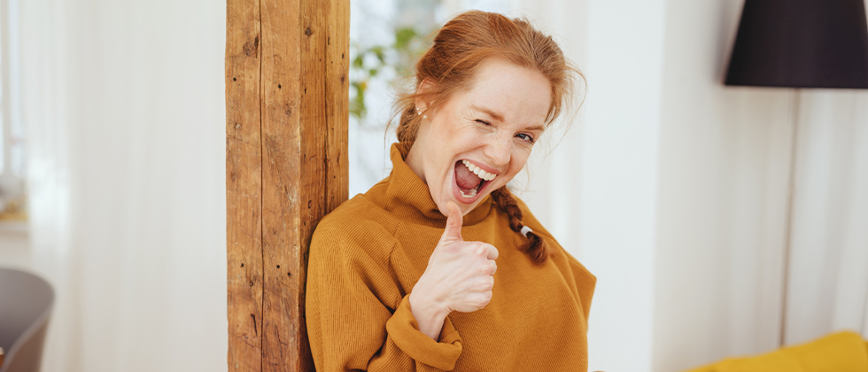 A woman gives a thumbs-up to camera, winking
