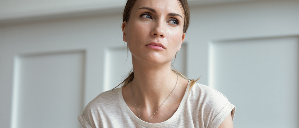 A woman stares into the distance, a look of worry on her face