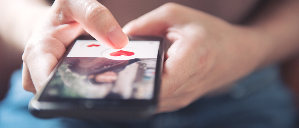 A woman hits the 'like' button on a dating profile on her phone