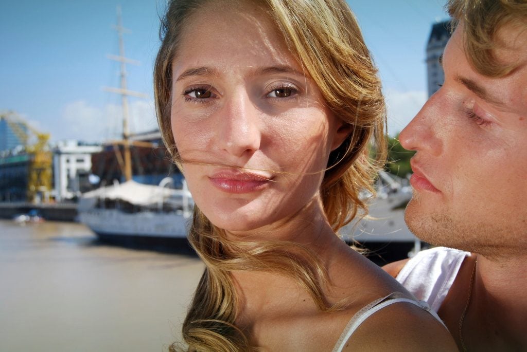 A women looking slightly away from a guy that wants to hug her.