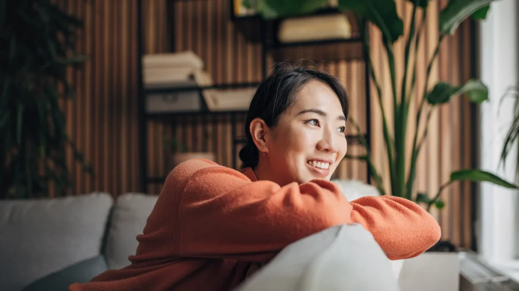 A women sitting on a couch and watching out of her window.