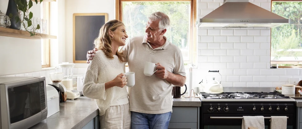 Couple standing in the kitchen drinking coffee and looking each other in the eyes