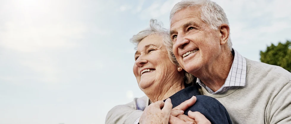 A man and a woman hugging each other and smiling.