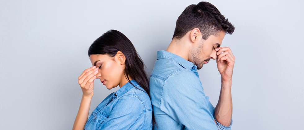 A couple standing back-to-back, looking worried
