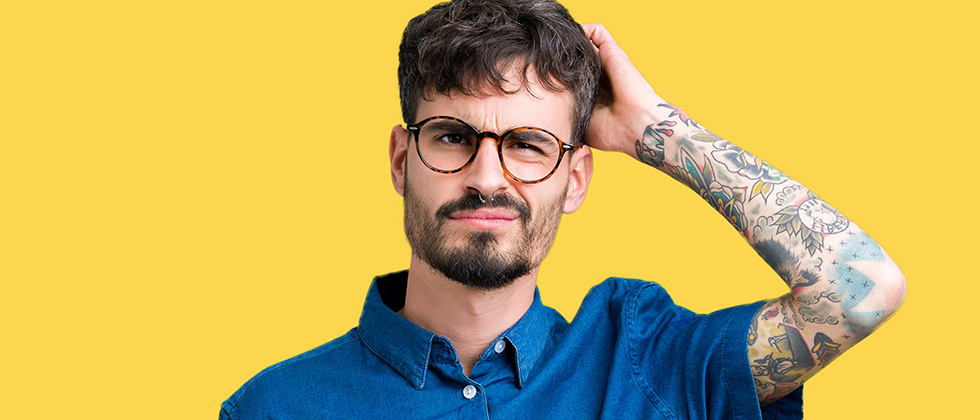A confused-looking man looks to camera, scratching his head