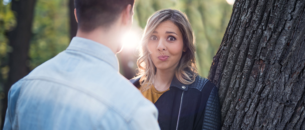 A woman looks over her partner's shoulder with an uncertain expression