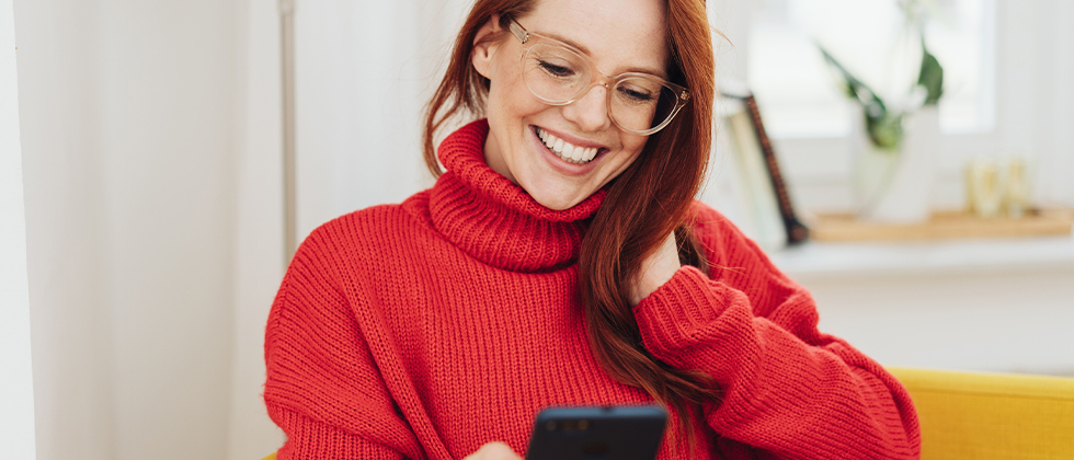 A woman smilling and looking at her phone