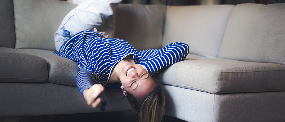 A woman sprawls on a sofa, her head hanging over the front edge
