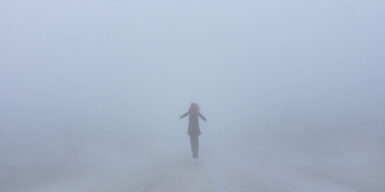 Someone standing at a distance in the middle of a foggy street