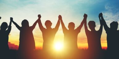 Group of friends holding hands in the sunset