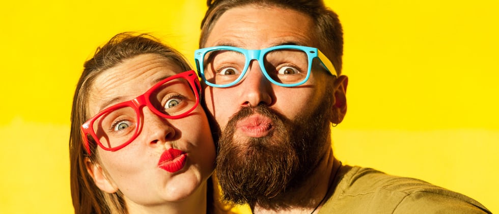 A couple being goofy wearing multi-colored glasses