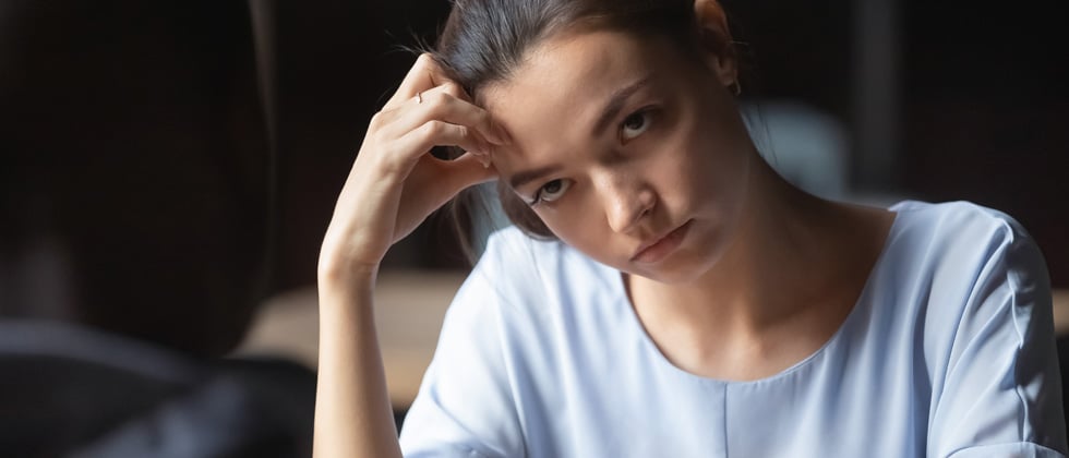 A woman looking annoyed while her head rests on her fist