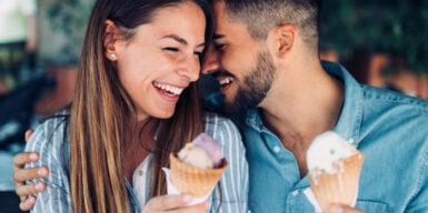 A cute couple flirting while eating ice cream cones together