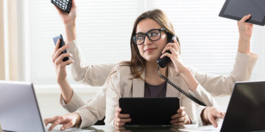 A woman sitting at a desk with 5 arms doing all different things