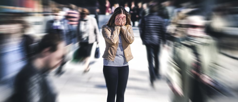 A woman covering her face with her hands in a crowd of people