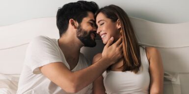 A couple sitting in bed about to kiss