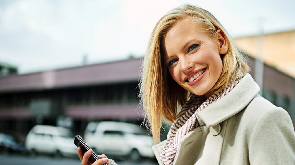 Woman with cell phone in hand starts free dating with eharmony