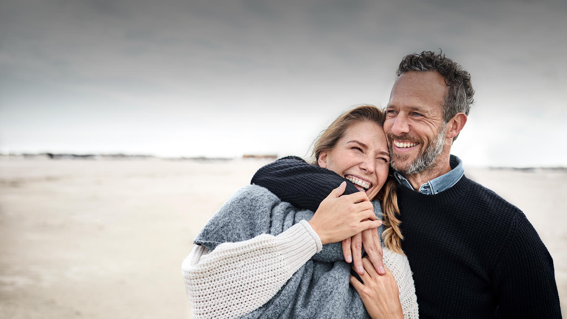 Catholic dating in Australia symbolized by a man who hold a woman in his arms at the beach