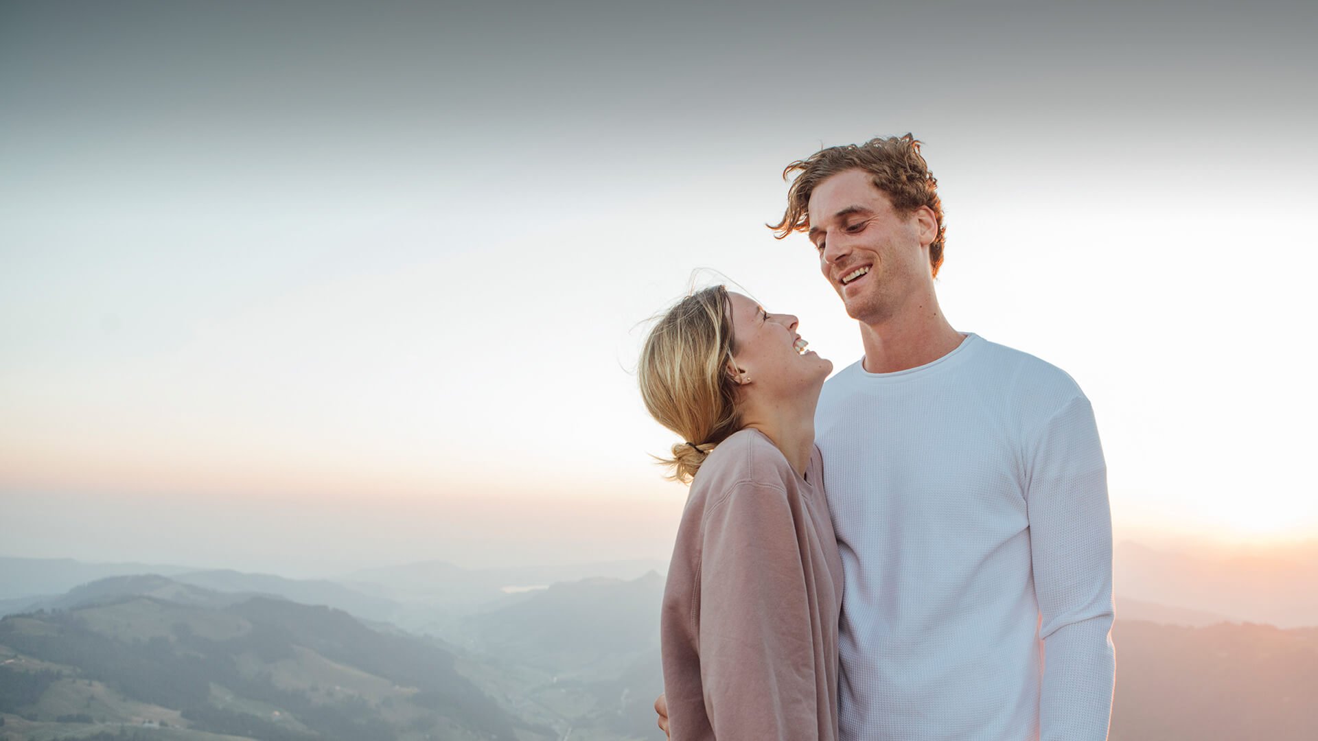 Divorced dating in Australia symbolized by a man and woman who stand close to each other in front of a romantic landscape