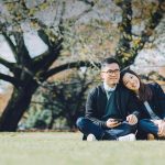 Japanese dating symbolized by a man and woman sitting cross-legged next to each other on a green field in Australia