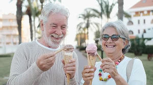 A couple eating ice cream next to plam trees.