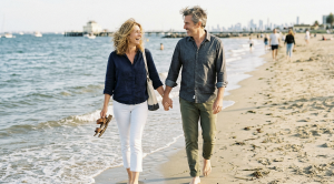 A couple walking next to the water at st kilda beach in melbourne.
