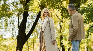 A couple walking in a park next to trees.