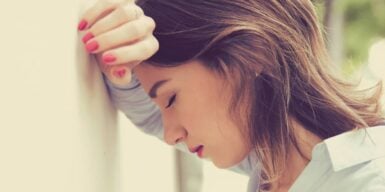 Frustrated woman leaning against a wall with her eyes closed