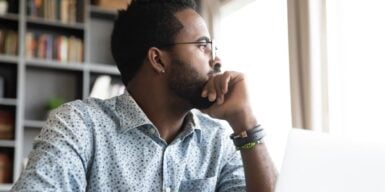 man sitting & looking into the distance deep in thought