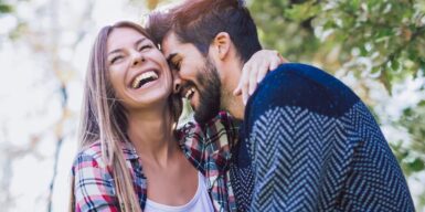 Happy couple cuddling and laughing in the sunlight