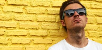 Young man leaning against a brick wall looking unapproachable