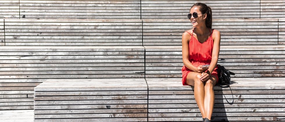 Pretty woman smiling and sitting alone on a park bench