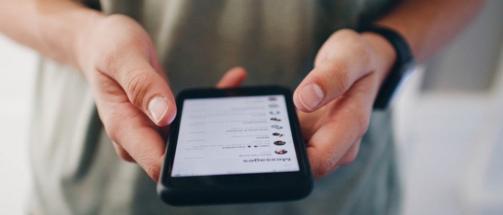 online dating first message smybolized by someone holding his smartphone between his hands and starting a conversation
