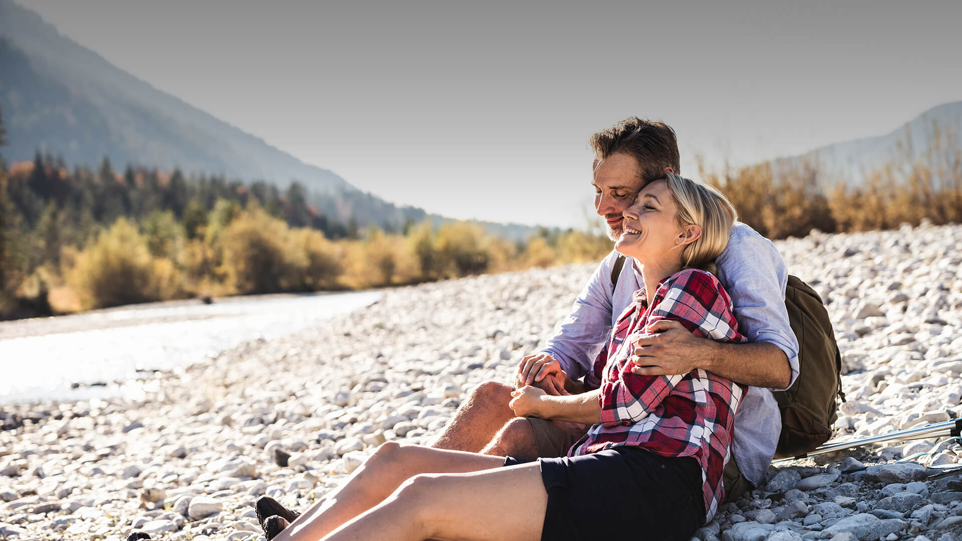 Mature women dating symbolized by a man and woman sitting at a river and enjoying the nature and their time together