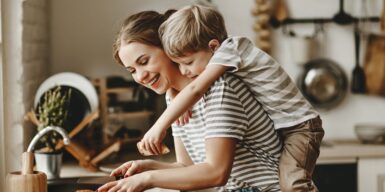 A mom cooking with her son on her back in the kitchen