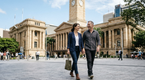 A couple walking hand in hand in front of brisbane city hall.