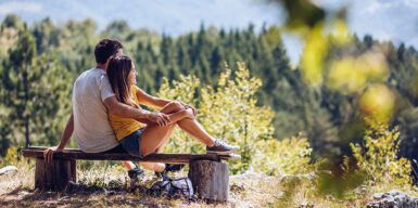 Young couple sitting on bench and enjoying in the beautiful view, on summer day as example for day date idea