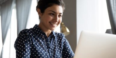 A woman smiling while looking at her laptop