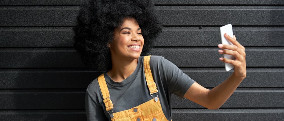 A young woman taking a selfie with a big smile on her face