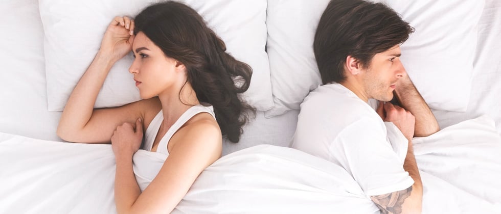 Man and woman in bed with their backs turned angry at each other