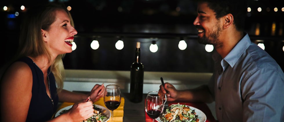 Man and woman have dinner together and laugh as a symbol for boyfriend material meaning