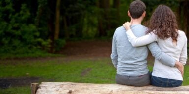 Couple sitting on a wooden bench holding each other