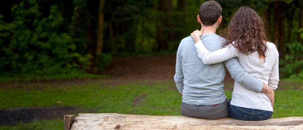 Couple sitting on a wooden bench holding each other