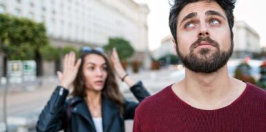 A woman and a man are standing on the street and seem to argue. The woman is looking angry and the man is annoyed.