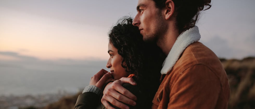 Man and woman lie in arms with view of mountains as symbol of fairytale love