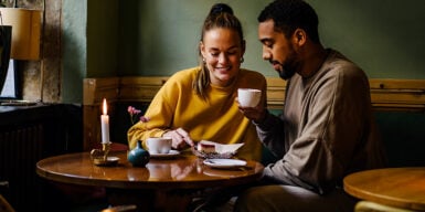 Man and woman drink a cup of coffee together and laugh and she thinks about how to ask for a second date