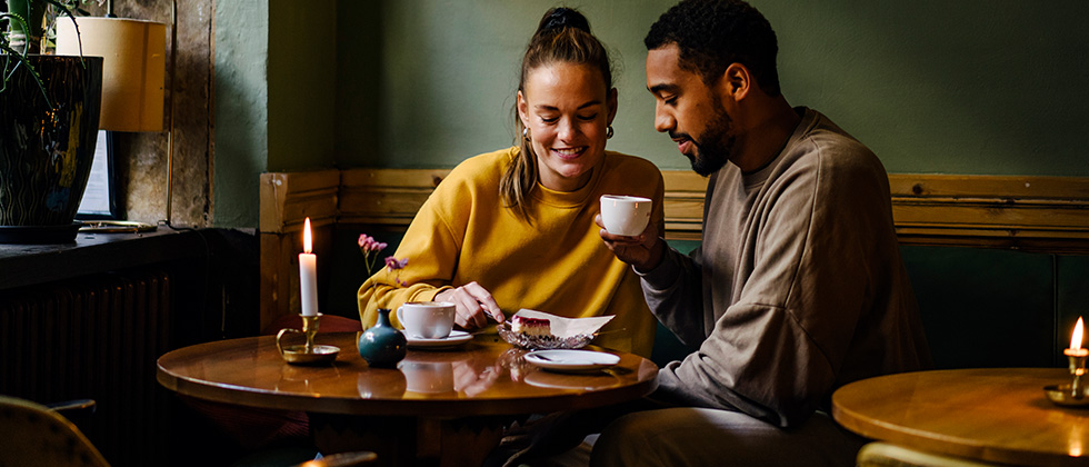 Man and woman drink a cup of coffee together and laugh and she thinks about how to ask for a second date