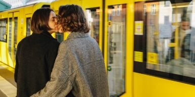 Man and woman kissing in front of arriving train as a symbol for how to get a girlfriend